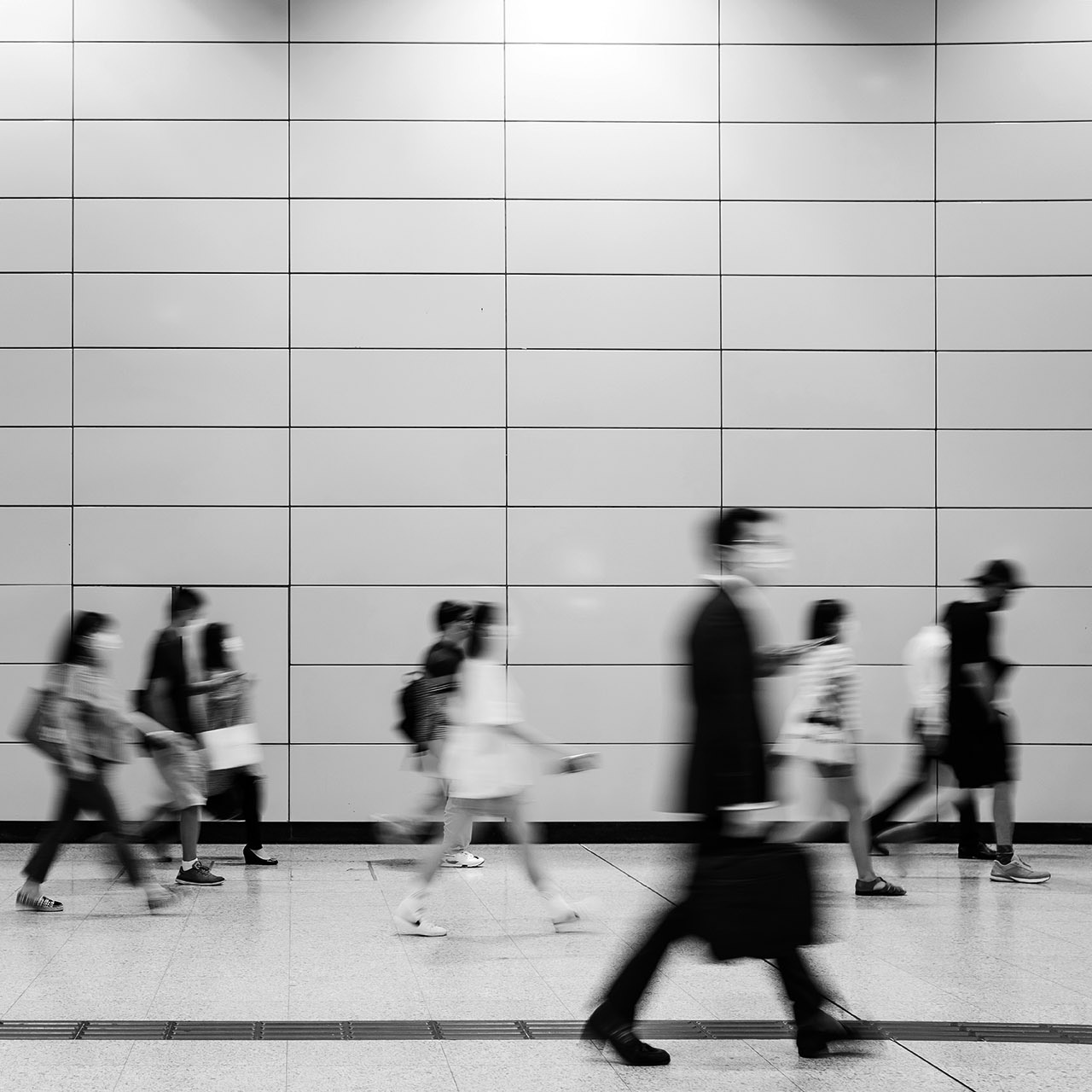 Blurred motion of a crowd of busy commuters with protective face mask walking through platforms at subway station during office peak hours in the city