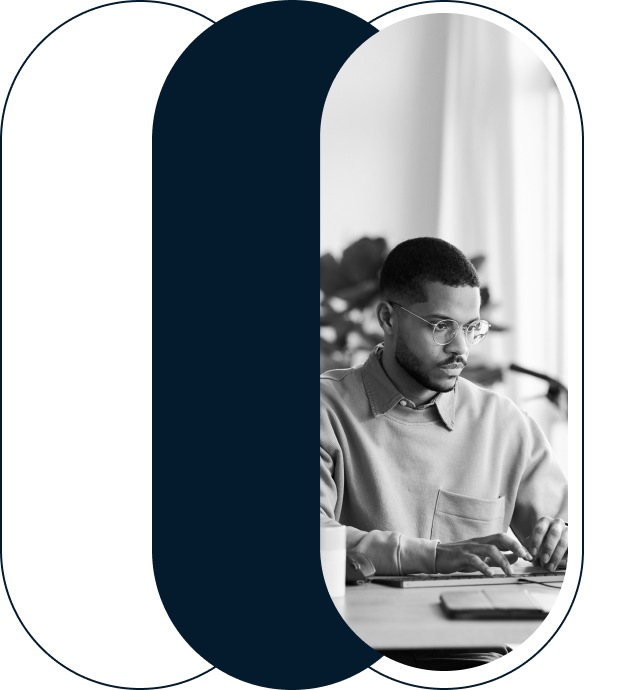 A black and white image of a man working at a desk.