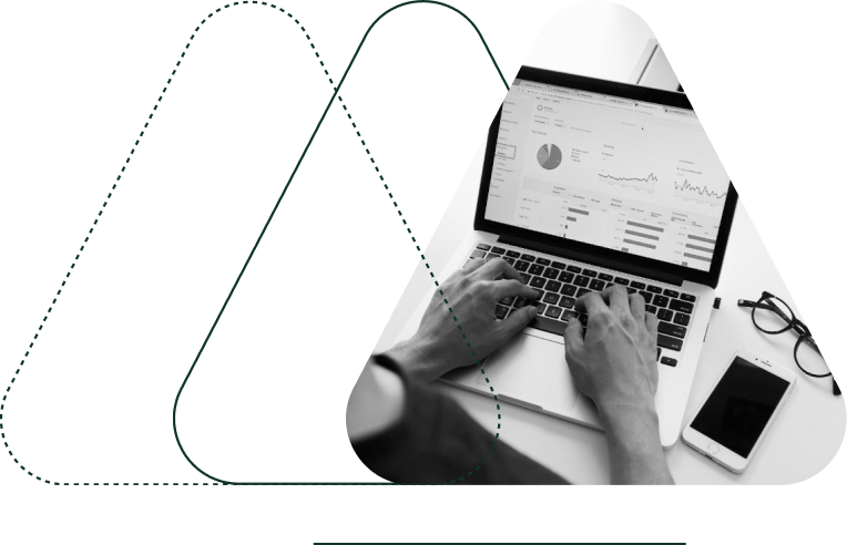 A person working on a laptop displaying charts and graphs, highlighting monetization solutions. Nearby, glasses and a smartphone rest on the desk. The image is overlaid with a geometric design.